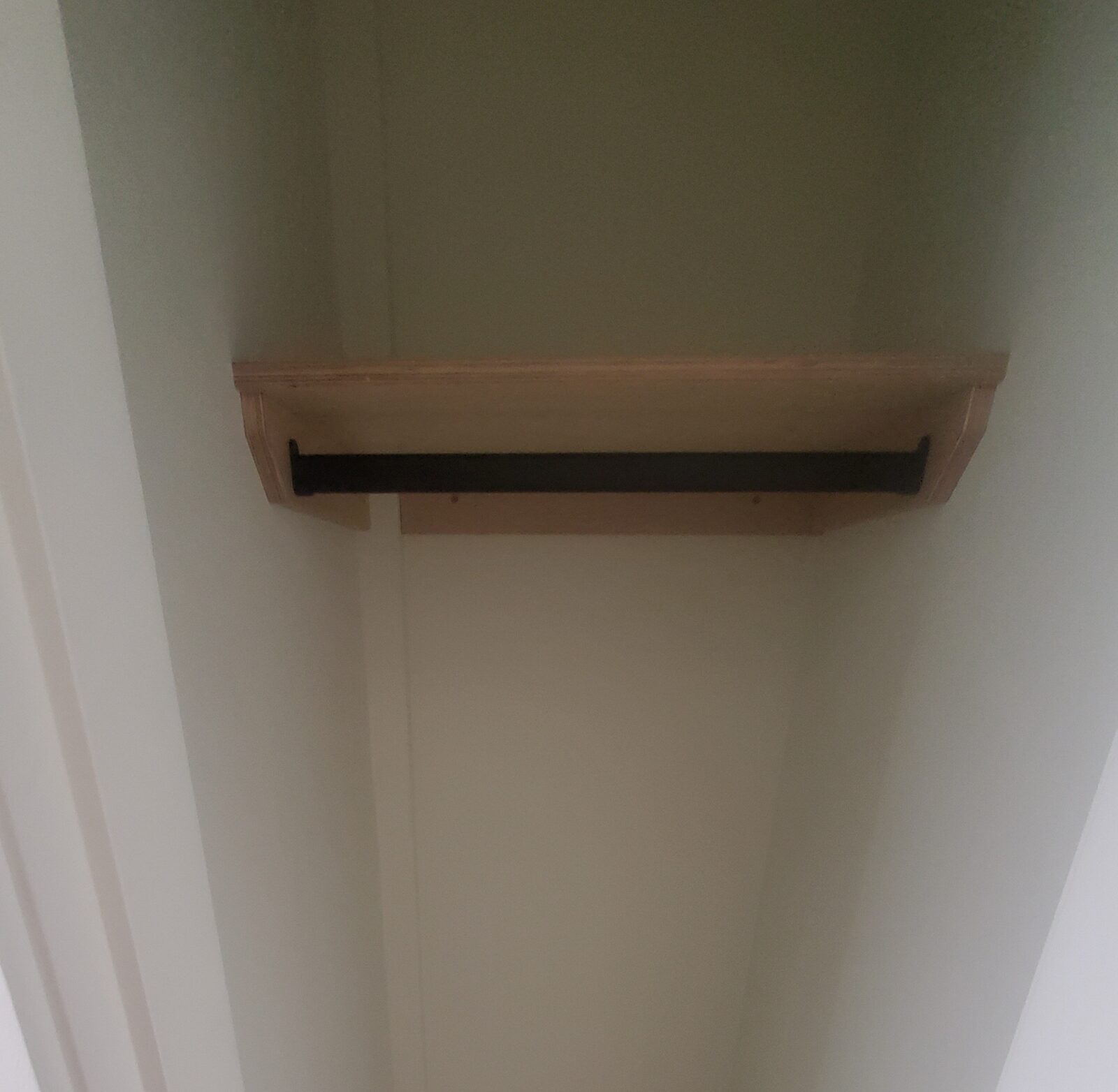 Finished built-in closet joinery with a solid hardwood shelf and matte black hanging rail