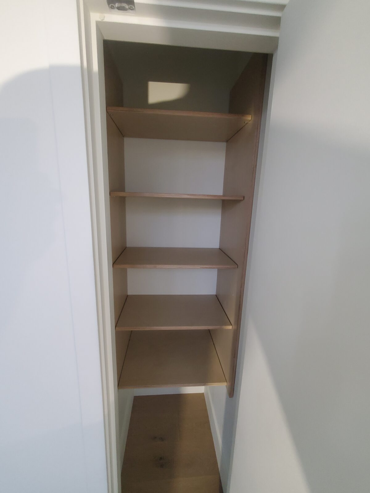 A minimalist birch plywood pantry shelving unit with clean exposed edges
